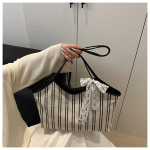 Detail of the black and white striped canvas tote bag with a white lace bow ornament