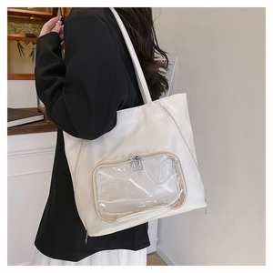 Dettaglio di una grande borsa tote in ecopelle crema con tasca trasparente indossata