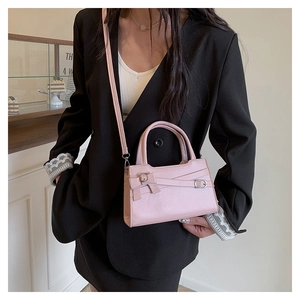Pink PU leather crossbody bag with bow detail and belt strap design on black blazer