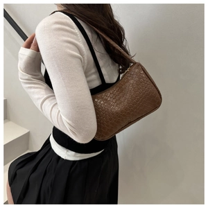 Vue détaillée du sac à bandoulière tressé marron foncé porté par le mannequin