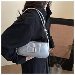 Detail of silver crescent underarm bag with belt buckle and knot strap on a model