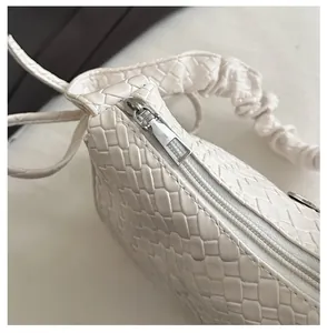 Detailed close-up of woven white leather texture with smooth metallic zipper closure