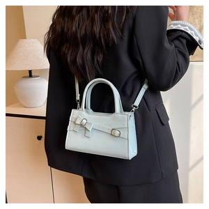 Detail of mint green square handbag with decorative bow and elegant silver metal hardware