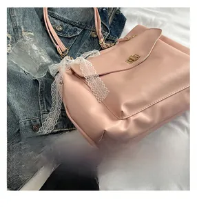 Détail du sac bandoulière rose avec boucle métallique dorée et bordure en dentelle