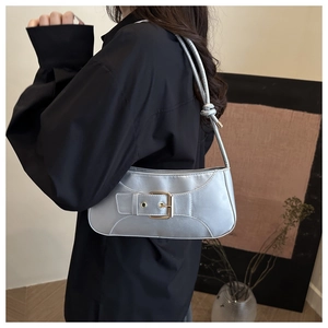 Detail of silver blue metallic underarm bag with golden buckle and sleek strap