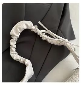 Detailed close-up of white woven texture and pleated handle on luxury shoulder bag
