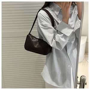 Detail of dark brown woven underarm bag showing intricate criss-cross texture and strap