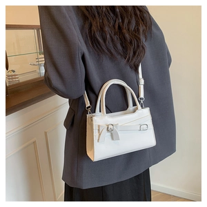 Close-up of elegant white PU leather handbag with decorative bow and silver metal buckle