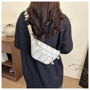 Detail of colorful striped nylon saddle bag with wide strap and dual zipper pockets