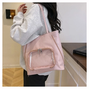 Dettaglio borsa tote rosa con tasca trasparente indossata a spalla in uno studio