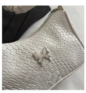 Detail showing creamy woven leather texture and silver butterfly buckle on the shoulder bag