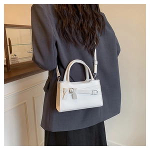 Detailansicht einer weißen Ledertasche mit Schnallenschleife an einem Modell