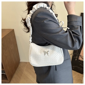Detail of white woven underarm bag featuring a silver butterfly buckle and ruched strap