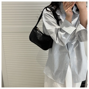 Close-up of black woven leather shoulder bag with gold zipper and textured check pattern