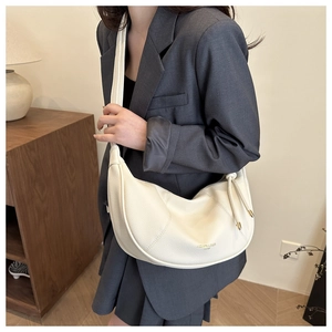 Detail of off-white leather hobo bag with grainy texture and drawstring side detail