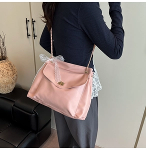 Détail du sac bandoulière rose clair avec grand nœud en dentelle blanche et fermoir doré