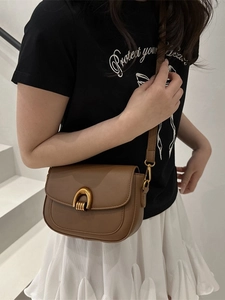 Sacoche marron en cuir avec boucle fer à cheval dorée portée par un mannequin femme