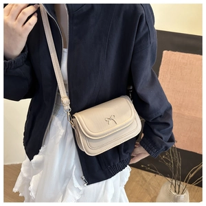 Close-up of beige crossbody bag featuring a golden bow metal buckle and adjustable strap