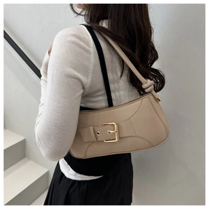 Detail of minimalist beige PU leather baguette bag with knotted strap on model shoulder