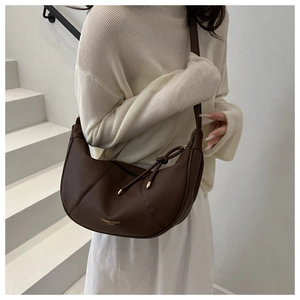 Detail of brown pebbled leather hobo bag with gold logo and drawstring knot decor