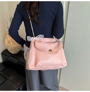 Sac bandoulière rose avec un grand nœud en dentelle blanche et un fermoir doré rotatif
