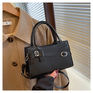 Detailansicht der schwarzen glänzenden Handtasche mit Schleife und silberner Schnalle