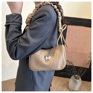 Detail of khaki faux crocodile texture and silver butterfly charm on crescent bag