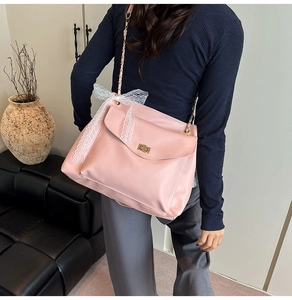 Détail du sac à bandoulière rose avec nœud en dentelle blanche et fermoir rotatif doré