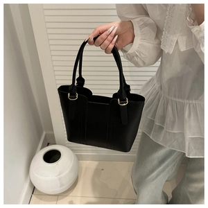 Vue détaillée d'un sac à main noir avec anneaux dorés et finition en cuir mat chic