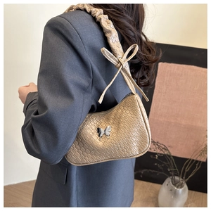Detailed shot of khaki woven texture bag with silver butterfly and pleated strap