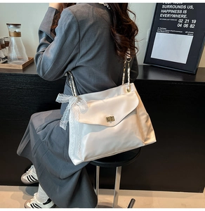 Détail du sac bandoulière en satin blanc avec grand nœud en dentelle et fermoir doré