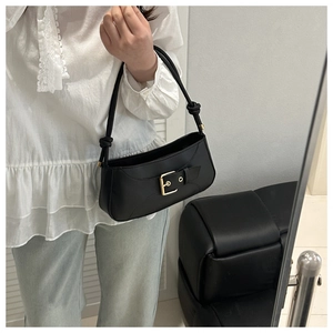 Close-up of black underarm bag with gold buckle and knotted strap detail for styling