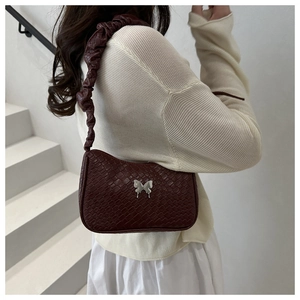Close-up of wine red woven PU leather underarm bag with silver butterfly metal detail