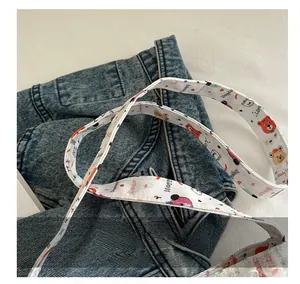 Detail of white canvas shoulder strap with colorful cartoon bears and heart patterns