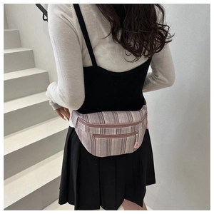 Detail view of large striped nylon chest bag showing retro pink zippers and fabric texture