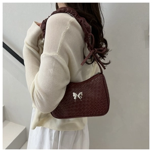 Detail of burgundy crocodile pattern leather bag with silver butterfly and pleated strap