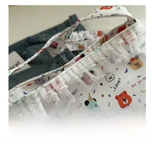 Detail of cute cartoon bear prints and delicate white lace trim on a canvas shoulder bag