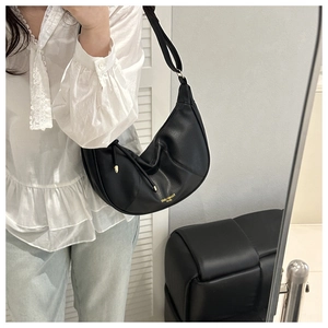 Close-up of black lychee texture hobo bag with gold logo and adjustable strap details