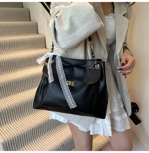 Détail du sac bandoulière noir en cuir PU avec serrure dorée et nœud en dentelle blanche