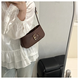 Detailed mirror selfie showing retro brown shoulder bag with gold buckle on white lace top