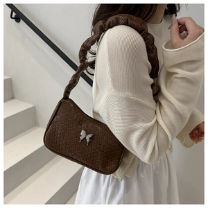 Detailed macro view of the silver butterfly buckle and braided handle on brown tote bag