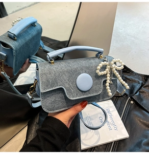 Gros plan du mini sac bleu clair texture denim avec breloque nœud perle et boucle ronde
