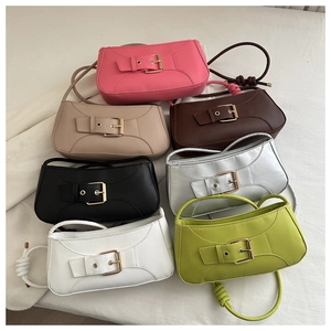 Flat lay of colorful shoulder bags with gold buckles and twisted straps on white fabric