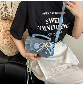 Détail du mini sac en denim bleu clair avec nœud en perles et pendentif cœur sur le mannequin