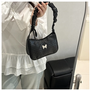 Detailed view of black woven shoulder bag with a silver butterfly buckle and pleated strap