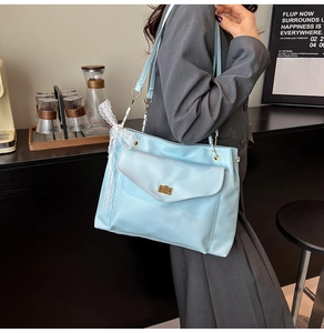 Détail du cabas en cuir verni bleu clair avec boucle dorée et accessoire en dentelle blanche