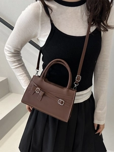 Brown leather crossbody bag with elegant bow design shown on a model at a stylish angle