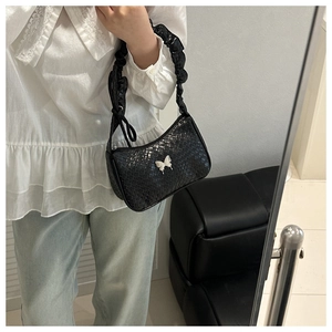 Detail of black woven shoulder bag with silver butterfly buckle and ruched handle