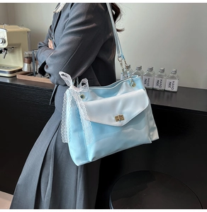 Détail du sac à bandoulière bleu clair avec nœud en dentelle blanche et chaîne dorée