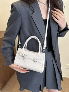 Chic cream leather handbag with bow detail and adjustable strap for elegant women